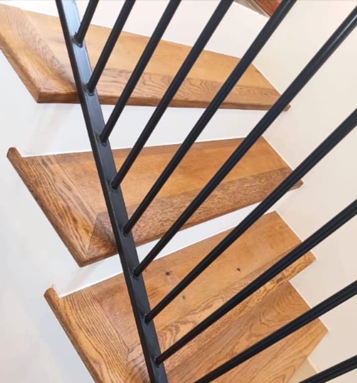 Finished solid wood staircase with a modern black metal railing